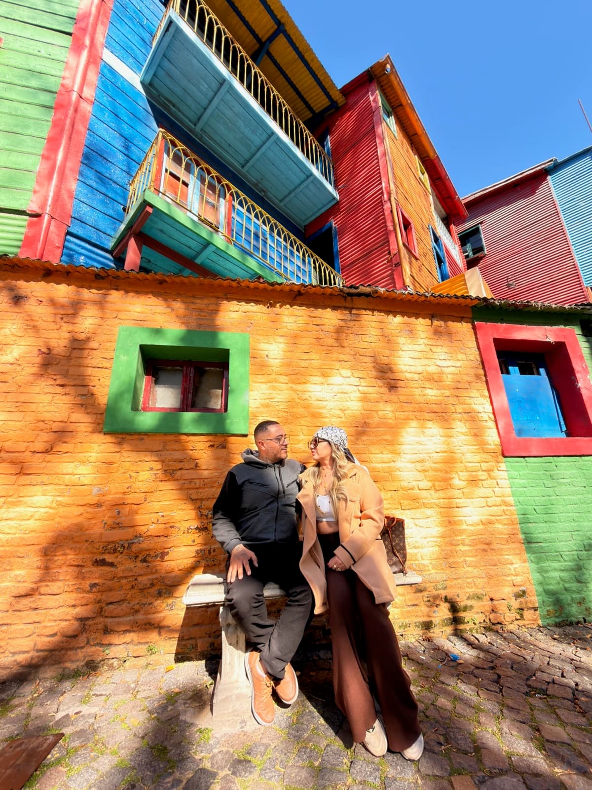 Casal de turistas nas casinhas coloridas do Caminito, Buenos Aires